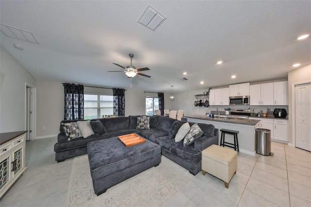 living area featuring light tile patterned floors, ceiling fan, recessed lighting, visible vents, and baseboards