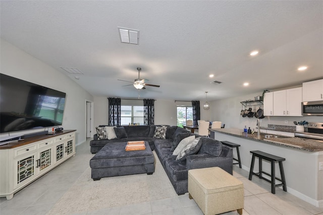 living area with visible vents, ceiling fan, and light tile patterned floors