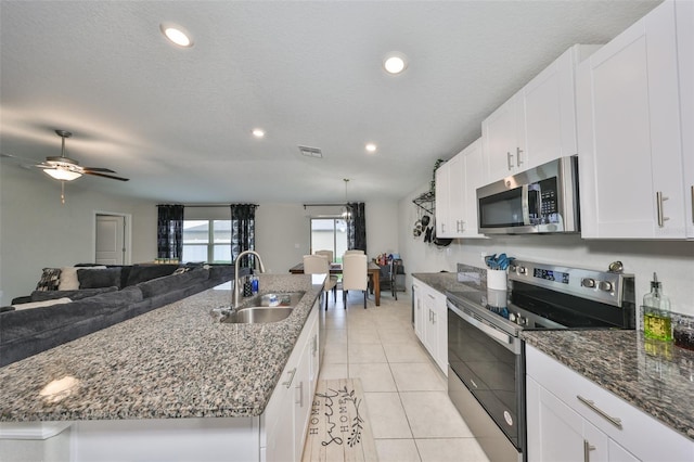 kitchen featuring a kitchen island with sink, appliances with stainless steel finishes, white cabinets, and a sink