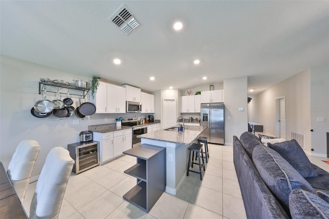 kitchen featuring visible vents, white cabinets, an island with sink, appliances with stainless steel finishes, and a sink