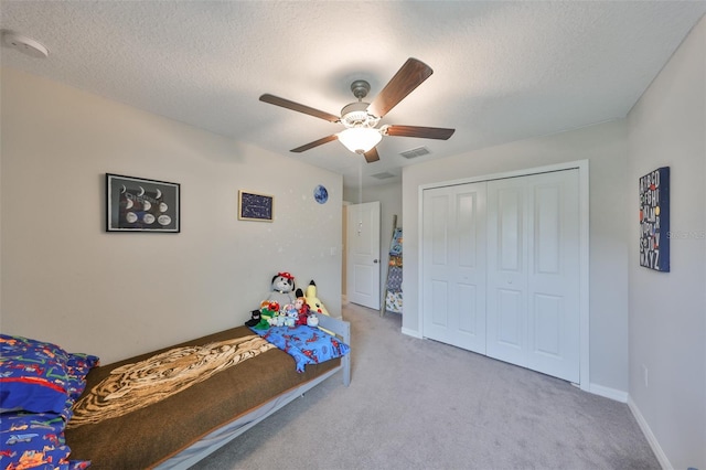 bedroom featuring a textured ceiling, light carpet, visible vents, a ceiling fan, and a closet