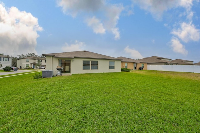 back of property featuring a yard, central air condition unit, fence, and stucco siding