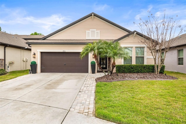 single story home featuring a front yard, driveway, and an attached garage