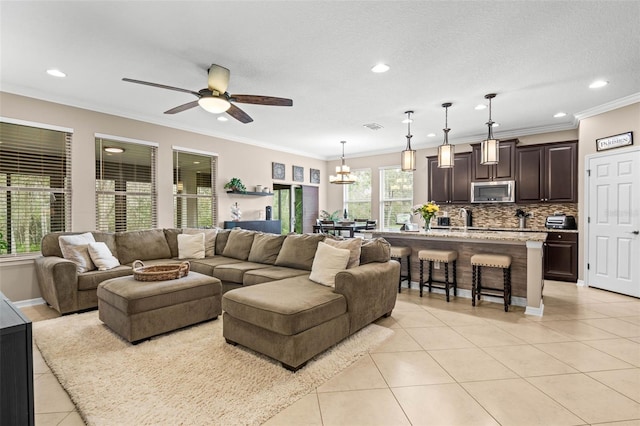 living area featuring light tile patterned floors, visible vents, ceiling fan, ornamental molding, and recessed lighting