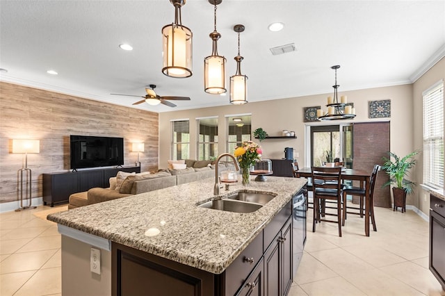 kitchen featuring an accent wall, a sink, visible vents, decorative light fixtures, and crown molding