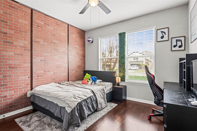 bedroom featuring brick wall, dark wood finished floors, and baseboards