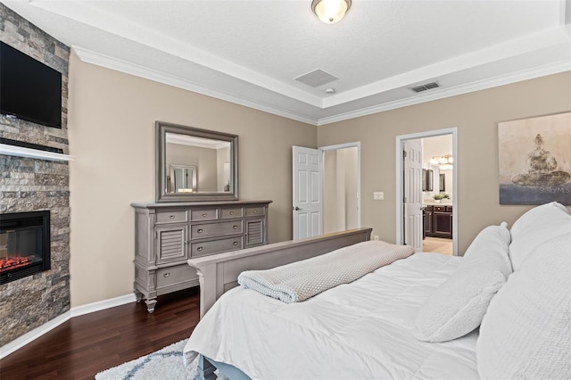 bedroom with connected bathroom, a fireplace, visible vents, baseboards, and dark wood finished floors