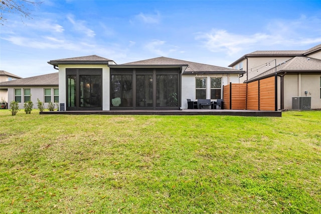 rear view of property with a sunroom, fence, central AC unit, and a yard