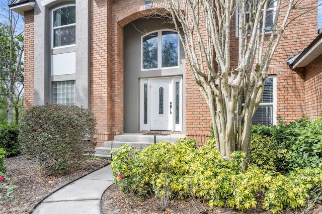 view of exterior entry with brick siding and stucco siding