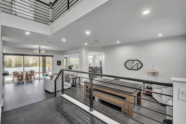 corridor with recessed lighting, a textured ceiling, and an upstairs landing