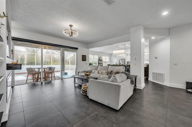 living room with baseboards, visible vents, a textured ceiling, and recessed lighting