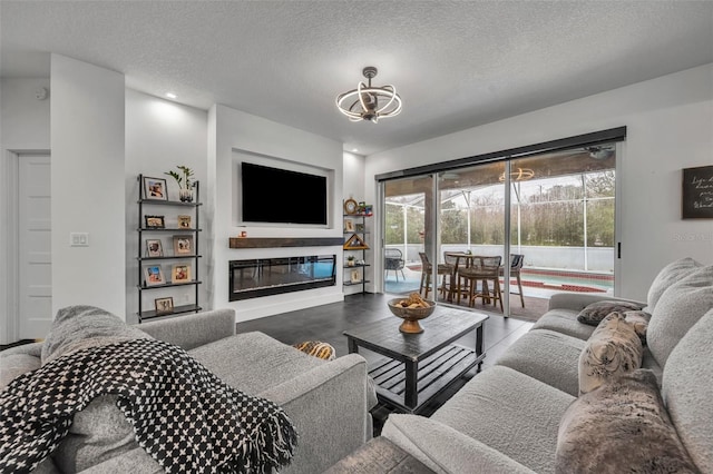 living room featuring a textured ceiling and a glass covered fireplace