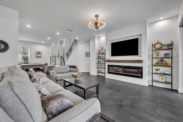 living room featuring recessed lighting, visible vents, a glass covered fireplace, baseboards, and stairs