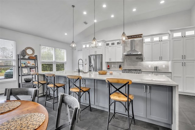 kitchen with wall chimney range hood, appliances with stainless steel finishes, glass insert cabinets, and a spacious island