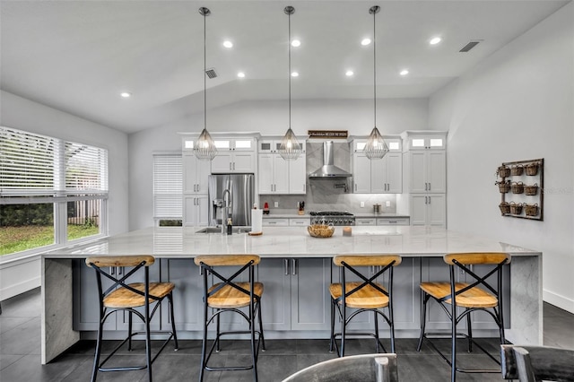 kitchen with wall chimney exhaust hood, glass insert cabinets, pendant lighting, and a breakfast bar area