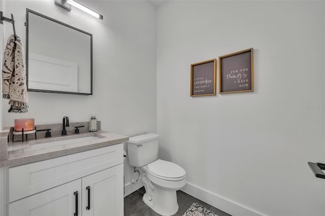 half bathroom with toilet, vanity, and baseboards