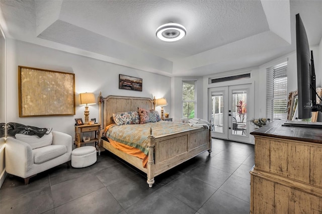 bedroom with access to exterior, a raised ceiling, a textured ceiling, and french doors