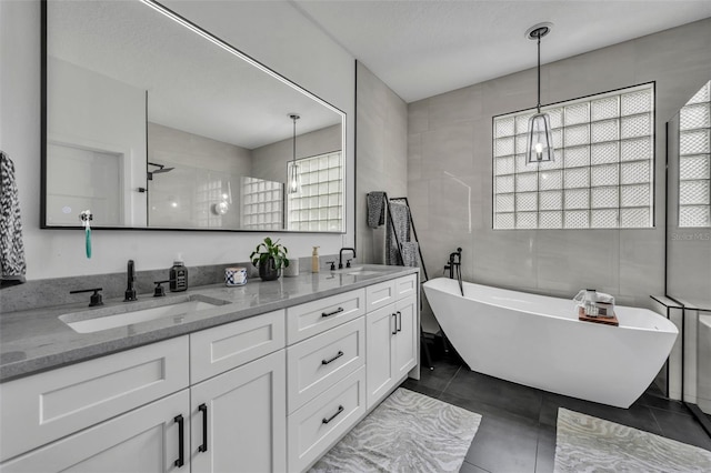 bathroom with a stall shower, a soaking tub, a sink, and tile patterned floors