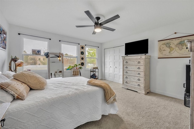 carpeted bedroom with ceiling fan, baseboards, and a closet