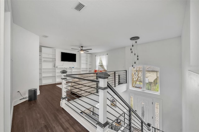 corridor featuring visible vents, dark wood-type flooring, and an upstairs landing