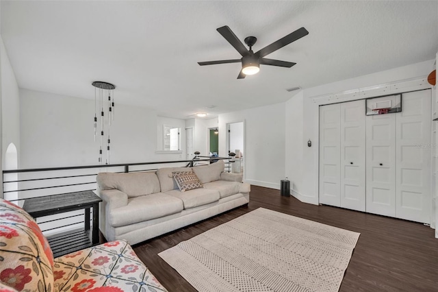 living area featuring a ceiling fan, dark wood-style flooring, visible vents, and baseboards