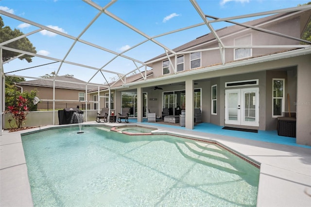 view of pool with french doors, a pool with connected hot tub, a patio area, glass enclosure, and an outdoor living space