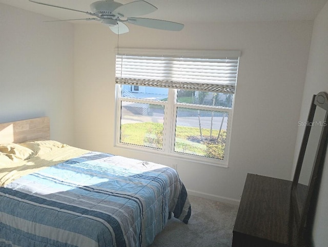 carpeted bedroom with ceiling fan and baseboards