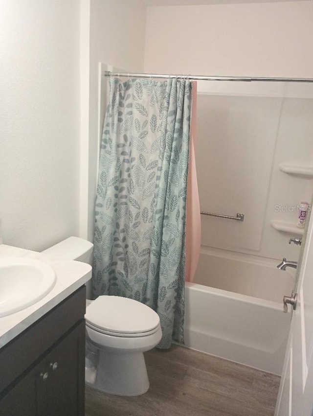 full bathroom featuring toilet, vanity, wood finished floors, and shower / tub combo with curtain