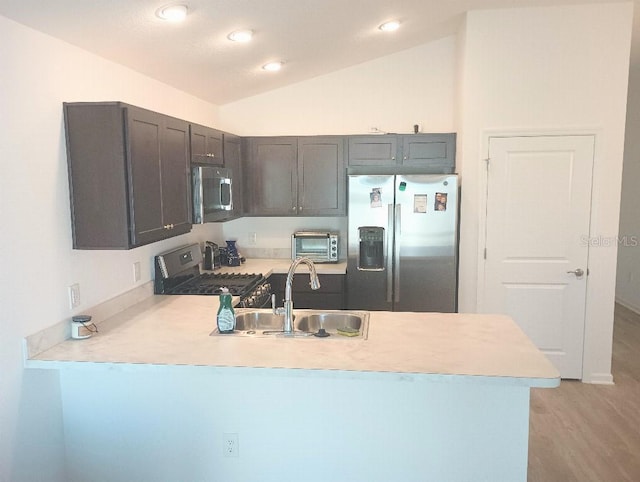 kitchen featuring light countertops, appliances with stainless steel finishes, a peninsula, and a sink