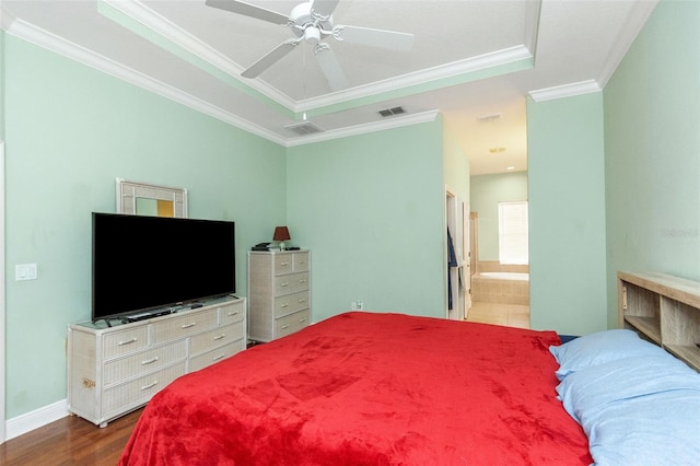 bedroom featuring dark wood-type flooring, a tray ceiling, visible vents, and crown molding