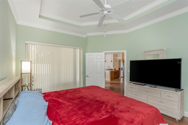 bedroom with ceiling fan, a tray ceiling, wood finished floors, and ornamental molding