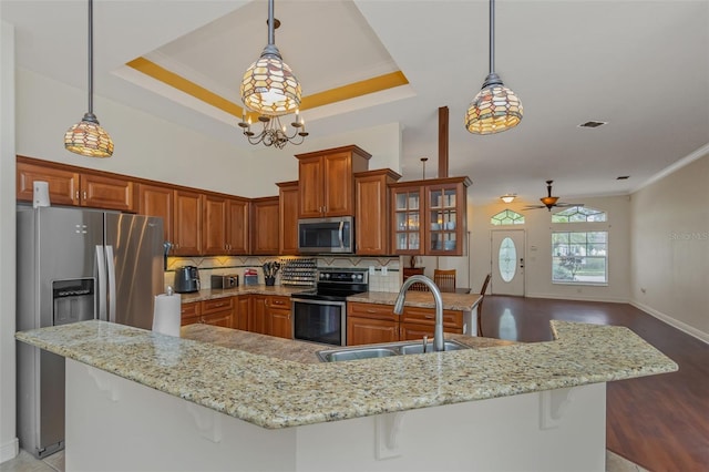 kitchen featuring stainless steel appliances, brown cabinets, a sink, and pendant lighting