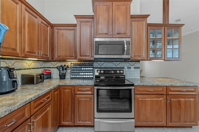 kitchen featuring appliances with stainless steel finishes, light tile patterned flooring, glass insert cabinets, and light stone countertops