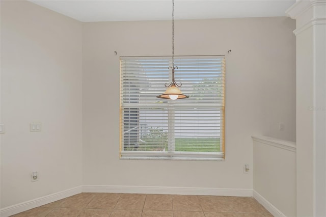 unfurnished dining area featuring light tile patterned floors, decorative columns, and baseboards