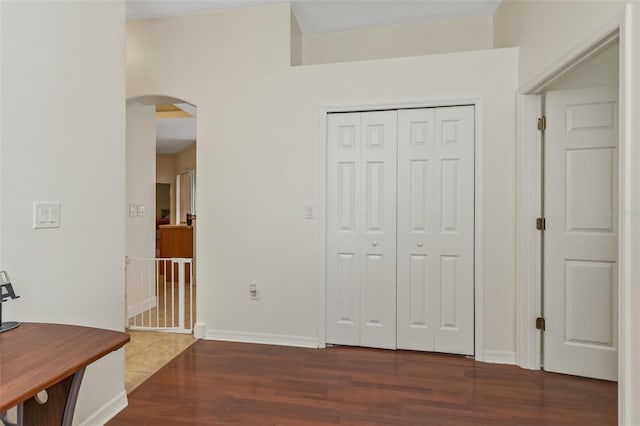 interior space with arched walkways, dark wood finished floors, and baseboards