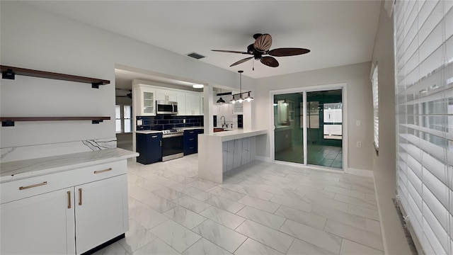 kitchen featuring pendant lighting, open shelves, stainless steel appliances, visible vents, and white cabinetry