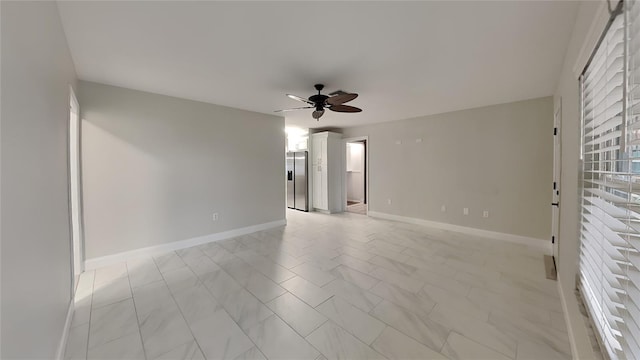 empty room featuring ceiling fan and baseboards