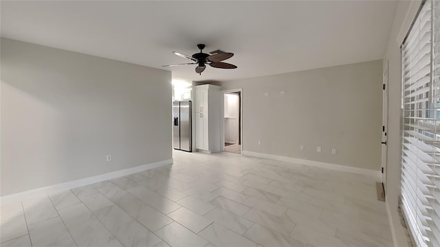 empty room with a ceiling fan and baseboards