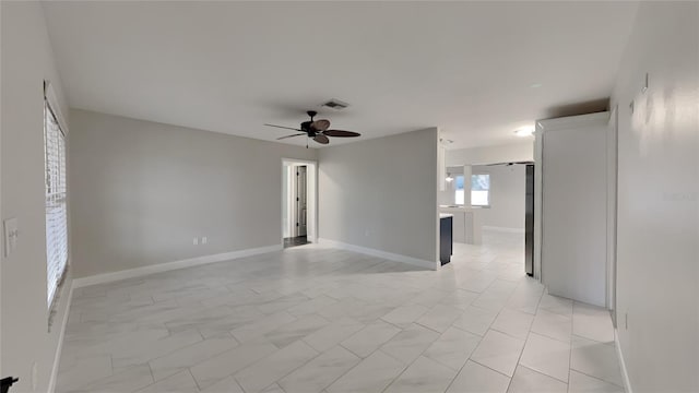 unfurnished room featuring ceiling fan, visible vents, and baseboards