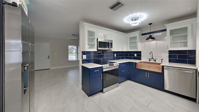 kitchen with stainless steel appliances, light countertops, glass insert cabinets, white cabinetry, and a sink