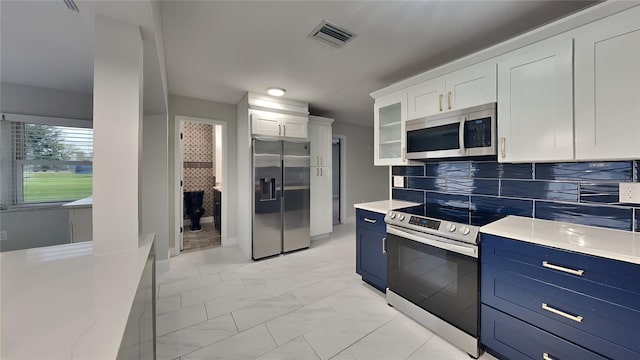 kitchen featuring blue cabinetry, stainless steel appliances, visible vents, glass insert cabinets, and white cabinetry