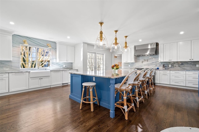 kitchen featuring wall chimney range hood and white cabinetry