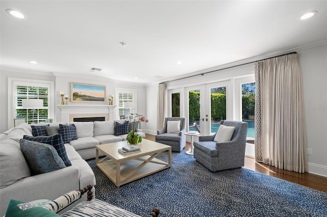 living area featuring french doors, ornamental molding, a fireplace, and wood finished floors