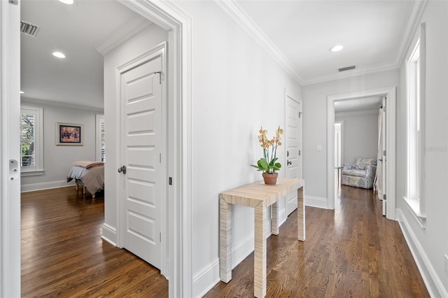 hall with dark wood-style flooring, visible vents, and crown molding