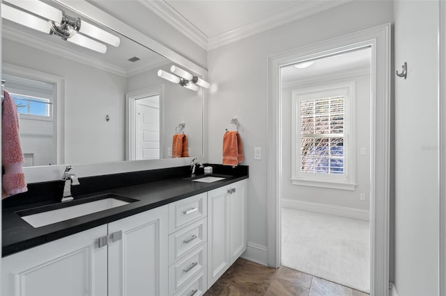 bathroom with a healthy amount of sunlight, ornamental molding, and a sink