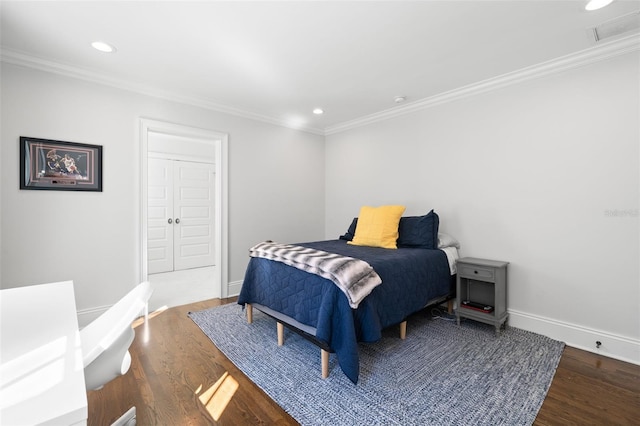 bedroom with wood finished floors, visible vents, and crown molding