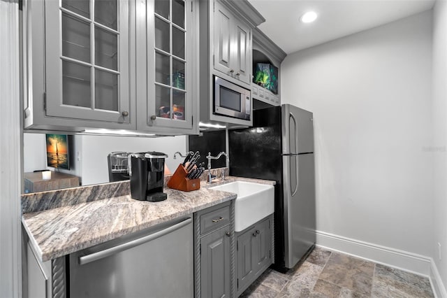 kitchen with stainless steel appliances, baseboards, glass insert cabinets, and gray cabinetry