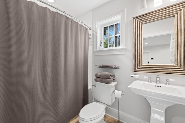 full bathroom with curtained shower, baseboards, and toilet