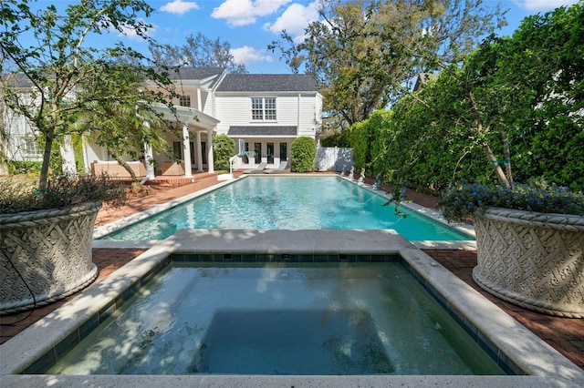 pool with french doors and an in ground hot tub