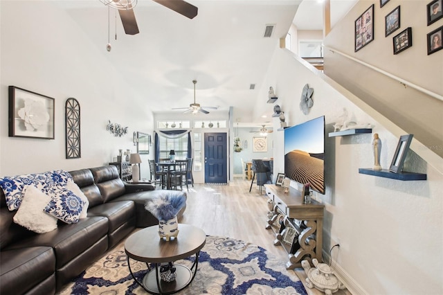 living area featuring visible vents, a high ceiling, wood finished floors, baseboards, and stairs